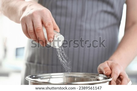 Chef Wearing Apron Adding Dish White Sea Salt. Male Hands Putting Spice to Saucepan. Man Cooking in Kitchen at Home. Preparing Organic. Food Culinary Recipe. Holding Shaker Horizontal Photography