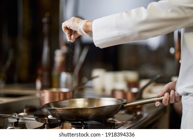 Chef In White Uniform Salting His Cooking In The Pan