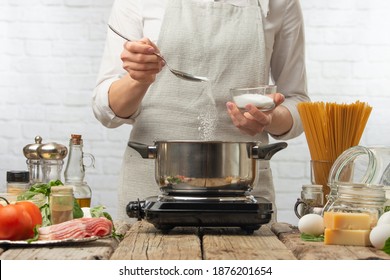 Chef in white uniform salts boiling water. Backstage of cooking pasta alla carbonara. Traditional italian dish on white background. Cooking process concept. Cookbook illustration.