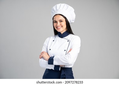 Chef mujer con uniforme y gorra de pie cruzó los brazos y posó sobre un fondo gris aislado. Concepto de ocupación