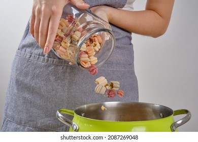 Chef woman's hands pour colored pasta from a glass jar into a green pan. Shallow depth of field - Powered by Shutterstock