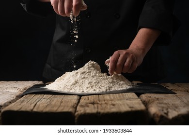 Chef works with flour for baking.On a black background, freeze in motion, horizontal photo - Shutterstock ID 1933603844