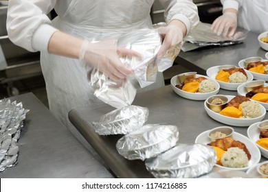 Chef is wrapping airline food in foil, professional kitchen - Powered by Shutterstock