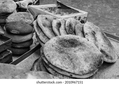 CHEFCHAOUEN, MOROCCO - Aug 31, 2018: A Grayscale Shot Of Hot Flatbreads For Sale In A Market In Narrow Street Of Chefchaouen Town, Morocco