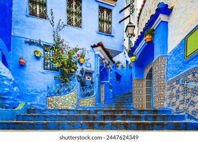 Chefchaouen, Morocco. Blue staircase and wall decorated with colourful flowerpots, Chefchaouen medina, North Africa travel destination.