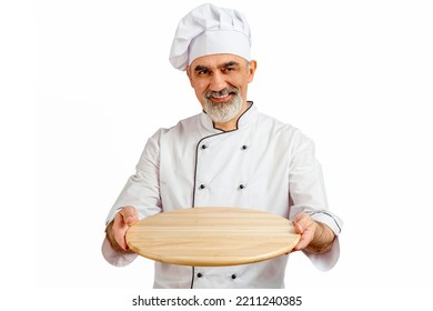 Chef-cooker in a chef's hat and jacket holding an empty wooden tray for mock up. Senior professional baker man wearing a chef's outfit. Character kitchener, pastry chef for advertising. - Powered by Shutterstock