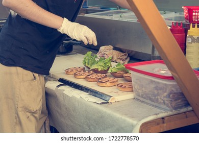 Cheff preparing delicious burgers - view from the side of food stand.