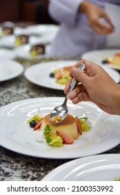 A Chef's Hand Garnishes A Plate Of Crème Caramel 