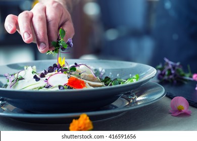 Chefs hand prepares a salad with chicken meat and decorates this meal with herbs and edible flowers. - Powered by Shutterstock