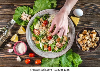 The Chef's Hand Is Putting The Crouton In The Salad. The Concept Of Cooking A Delicious Appetizing Caesar Salad