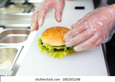 The chef's hands demonstrate the finished Burger. Preparing burger in restaurant. Hands of the cook in disposable gloves based on hygiene requirements. - Powered by Shutterstock