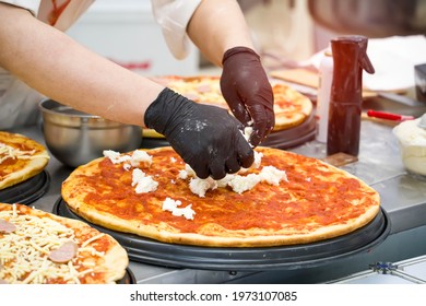 Chefs Hands In Gloves And Preparing Making Pizza At Kitchen.