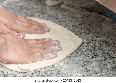 Chef's Hands Kneading A Pizza On Gray Granite Countertop