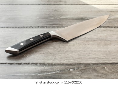 Chef's Knife On Wooden Boards Desk.