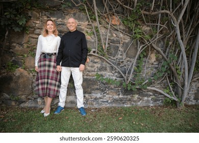 Chefs posing holding hands in front of stone wall with vines