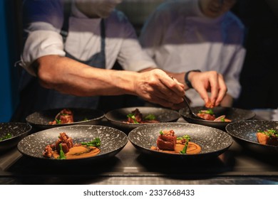 chefs preparing food in professional kitchen. Focus on dish of dinning food in front row. Chef blur as  background. - Powered by Shutterstock