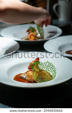 Chefs standing at table in kitchen and decorating beautiful dishes in restaurant