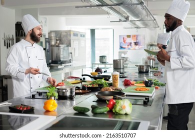 Chefs talking about what meal to prepare for dinner service at fine dining restaurant. Diverse food industry workers discussing about gourmet dish recipe while cooking in professional kitchen. - Powered by Shutterstock