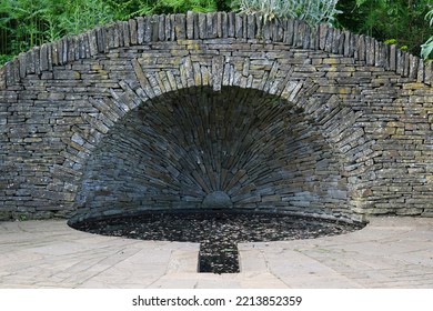 Chelmsford, Essex, United Kingdom, May, 28, 2022. Ornamental Dry Stone Wall Slate Bridge And Water Feature Pond Or Pool In Hylands House Public Park Formal Gardens. Elegant Garden Design Element