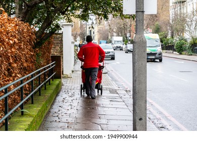 CHELSEA, LONDON, ENGLAND- 17th February 2021: Royal Mail Postal Worker Pushing A Post Trolley In Chelsea