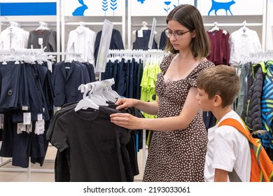 Chelyabinsk, Russia, August 2022. A Young Mother And A Little Boy Choose A Shirt At The Mall, Selective Focus. The Family Buys School Clothes For The Child. Back To School