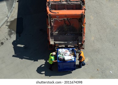 Chelyabinsk,Chelyabinsk Oblast, Russia-June 28.2021 Garbage Removal. The Scavengers Are Rolling The Trash Can To The Garbage Truck, Top View. Garbage Loading Process.