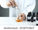 chemical beaker , flask is on white table with blotting paper , fragrance bottle and essential oil bottle are used to blend the nice scent for making perfume and reed diffuser by perfumer in lab