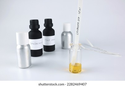 chemical beaker , flask is on white table with blotting paper inside , fragrance bottle and essential oil bottle are used to blend nice scent for making perfume and candle by perfumer in laboratory
