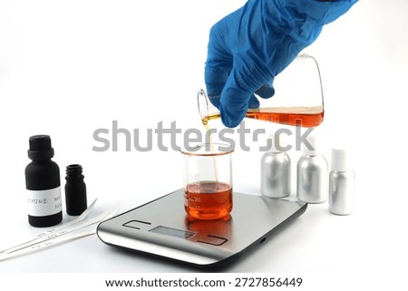 chemical beaker or flask is used on white table with blotting paper fragrance bottle and essential oil bottle are used to blend nice scent for making perfume and reed diffuser by perfumer in lab test