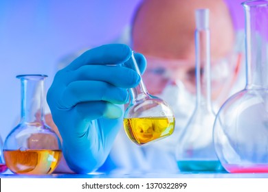 Chemical Examination Of Food. Chemist Conducts A Test. Researcher Studies The Results Of The Experiment. Chemical Laboratory. Chemist In A Protective Mask And Glasses. Respiratory Protection.