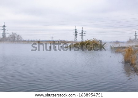 chemical fumes in the form of fog over the autumn lake on the shore of which there are power lines
