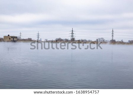 chemical fumes in the form of fog over the autumn lake on the shore of which there are power lines