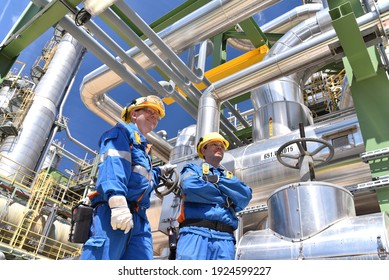 chemical industry plant - workers in work clothes in a refinery with pipes and machinery 