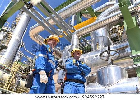 chemical industry plant - workers in work clothes in a refinery with pipes and machinery 