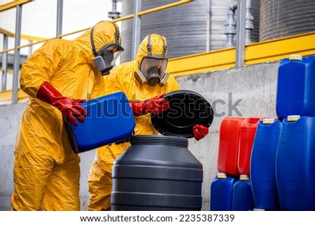 Chemical plant workers in hazmat suit mixing chemicals and manufacturing acids for heavy industry.