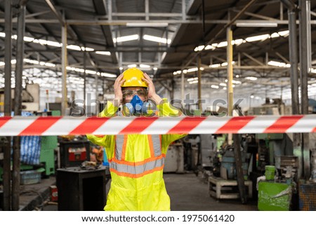 Chemical specialist wear safety uniform and gas mask raising his hands on head and scared while standing near chemical dangerous area in industry factory behind line area barrier red and white colour