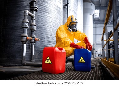 Chemicals industry for acid production. Factory worker in hazmat protective suit and gas mask carefully working with hazardous materials. - Shutterstock ID 2292750453