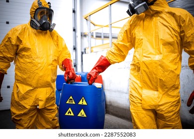 Chemicals production factory. Experienced workers fully protected in gas mask carrying hazardous and toxic waste in chemical plant. - Shutterstock ID 2287552083