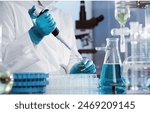 Chemist is conducting research by using elenmeyer glass, beaker glass, chemical, and natural ingredient of plants  for producing a beauty product