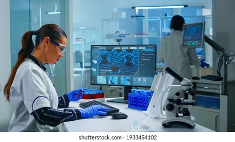 Chemist Doctor Holding Test Tube With Blood Sample Entering Datas In Pc Working In Lab. Team Of Scientists Analysing Vaccine Evolution Using High Tech Researching Diagnosis Against Covid19 Virus.