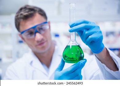 Chemist Holding Up Beaker Of Green Chemical In The Laboratory