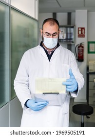 Chemist Reviewing A Work Report. Lab Technician With Protective Mask Looking At Technical Data. Photography Vertical