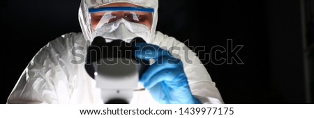 Chemist Scientist Analyzing Microscope Research. Science Research in Medical Laboratory. Worker in Respirator and Coverall Working on Chemical Experiment with Equipment. Male in Protective Eyeglasses