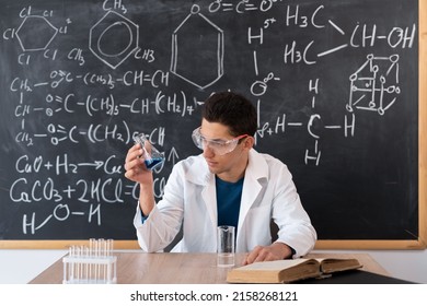 Chemist Scientist Examines A Flask With Reagent. Arab Student Mixes Chemicals In A Flask. Focused Teacher Giving Chemistry Lesson, Muslim Laboratory Chemist Showing New Experiment Of Science Class