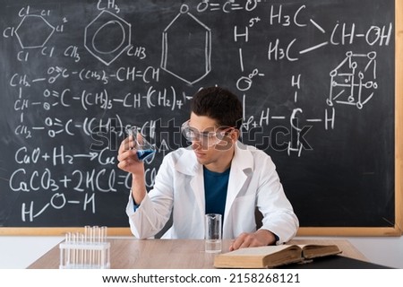 Chemist scientist examines a flask with reagent. arab student mixes chemicals in a flask. focused teacher giving chemistry lesson, muslim laboratory chemist showing new experiment of science class
