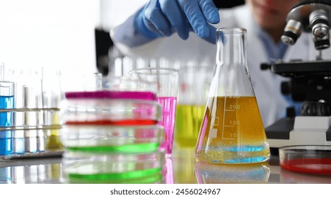 Chemistry industry lubricant oil test concept. Female chemist in blue protective gloves hand hold test tube with yellow liquid. Make analysing sample petroleum gasoline fuel in chemical laboratory. - Powered by Shutterstock