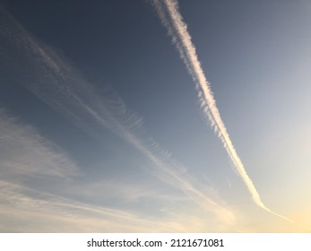 A chemtrail in the sky at the sunset. Clouds and chemtrail at the sunset light in the sky