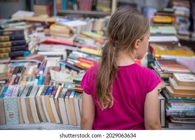 Chengdu, China - July 2019 : Young Caucasian girl looking at the pile of second hand books for sale on a street market - Powered by Shutterstock