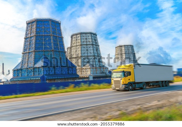 Cherepovets,\
Russia 08 October 2021 Metallurgical plant pipes. A yellow truck in\
soft focus rushes along the highway. Freight transport of metal,\
delivery of metallurgical products by road.\
