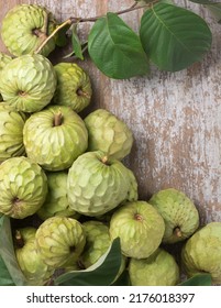 Cherimoya, Annona Cherimoya, Cone Shaped Edible Fruit Also Known As Custard Apple Or Sugar Apple, Pile Of Sweet Taste Tropical Fruit With Leaves On A Wooden Table Top, Copy Space